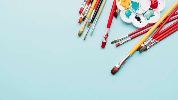 Crayons et pinceaux posés sur une table claire pour une activité créative